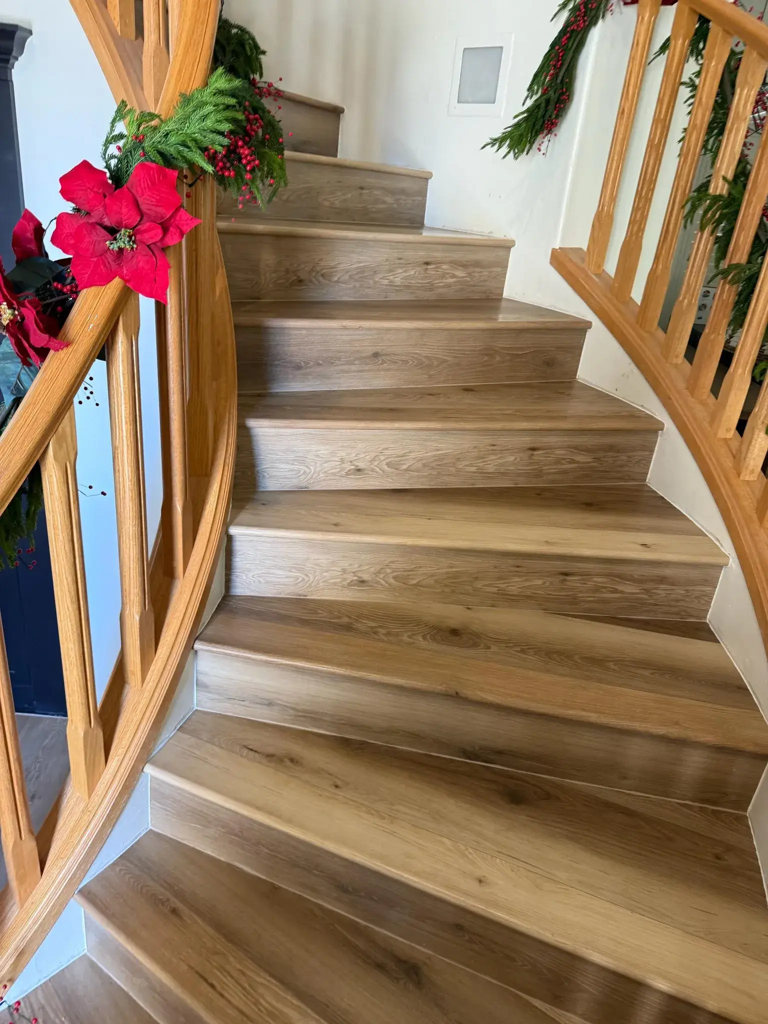 Curved hardwood staircase with light oak treads, white risers, and matching wood handrail installed by Zona Floors in Arizona