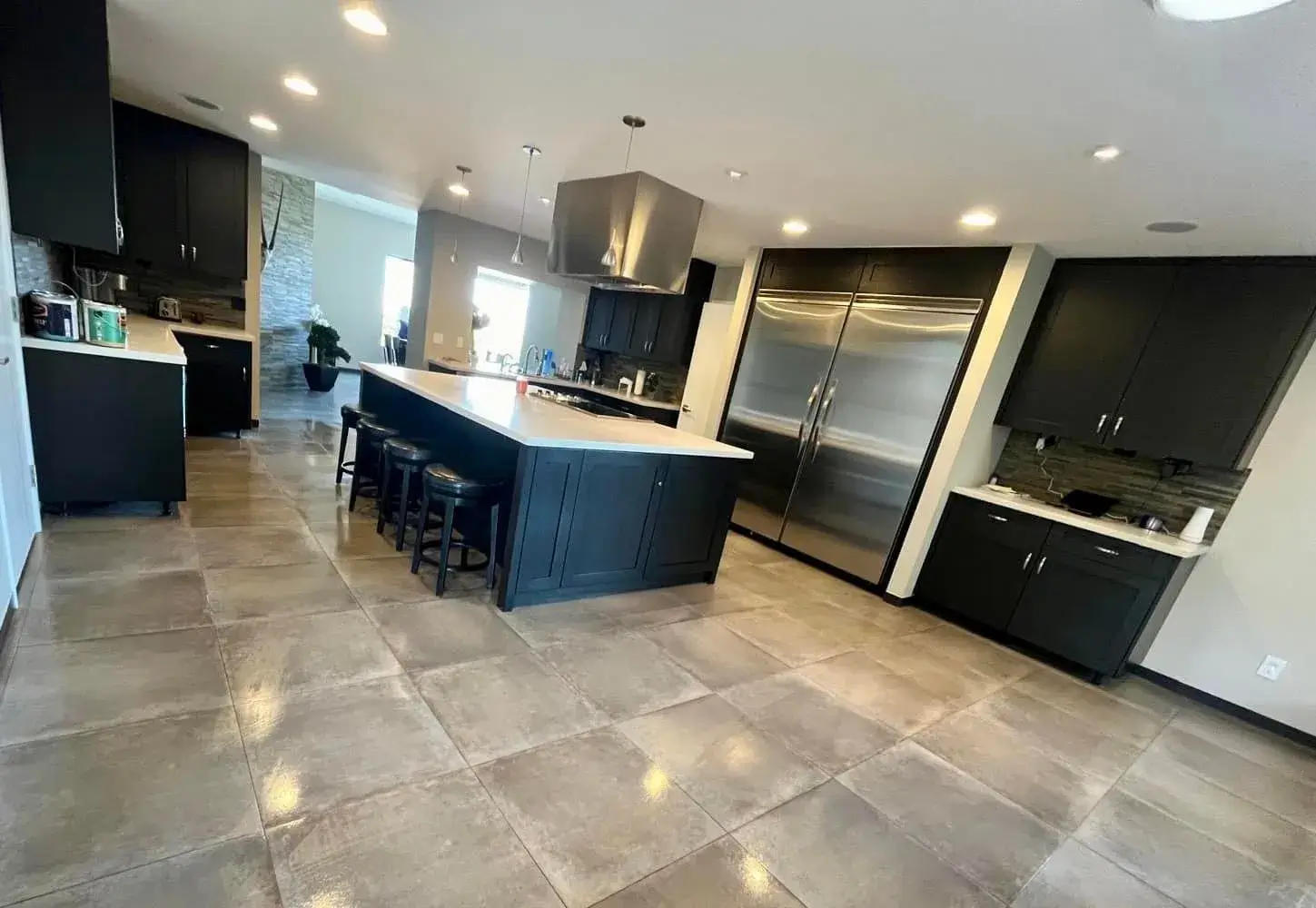 Open Arizona kitchen with dark cabinets, large island, and large-format porcelain tile flooring installed by Zona Floors